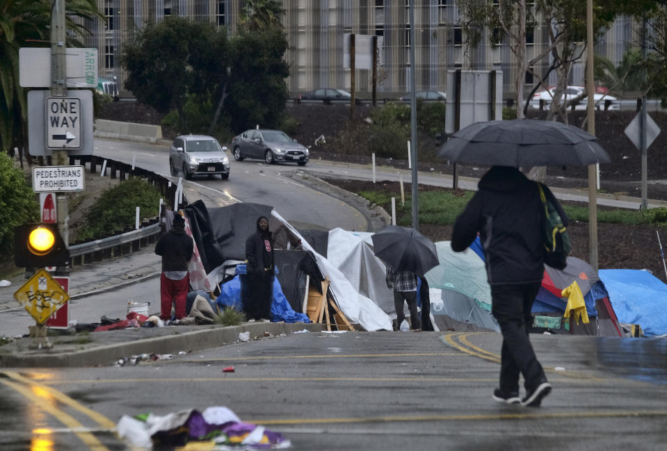 FILE - In this Jan. 17, 2019, file photo, pedestrians make their way along a rain soaked Hollywood Blvd., in Los Angeles. Mayor Eric Garcetti is paying a political price for the city's homeless crisis. An effort is underway to recall the two-term Democrat from office prompted by widespread complaints about homeless encampments throughout the city. Figures released earlier this month showed a 16% jump in LA's homeless population over the last year, pegging it at 36,300, the size of a small city. (AP Photo/Richard Vogel, File)