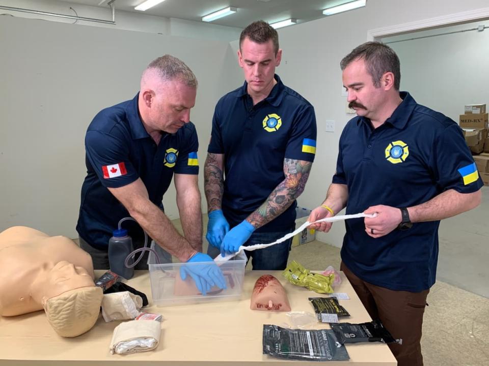 Kevin Royle, Nelson Bate and Anatoli Morgotch of Firefighter Aid Ukraine demonstrate some of the combat first aid training that they taught participants in Ukraine. (Julia Wong/CBC - image credit)