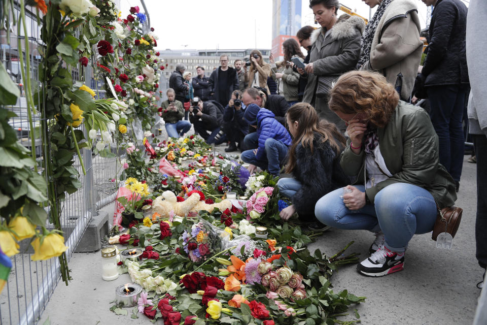 People lay down flowers at a fence near the department store Ahlens following a suspected terror attack in central Stockholm, Sweden, Saturday, April 8, 2017. Swedish prosecutor Hans Ihrman said a person has been formally identified as a suspect "of terrorist offences by murder" after a hijacked truck was driven into a crowd of pedestrians and crashed into a department store on Friday. (AP Photo/Markus Schreiber)