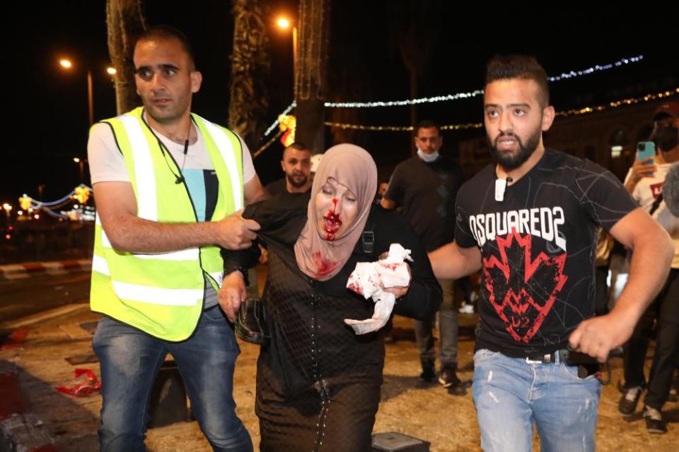 People help an injured Palestinian woman during a protest in Damascus gate supporting Palestinian families that face eviction from their homes at Sheikh Jarrah neighborhood, in Jerusalem.