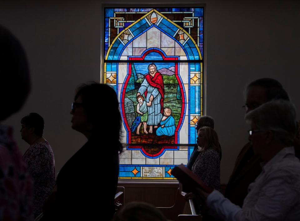 Light shines from a stained glass window depicting Jesus and two children during a Palm Sunday service at  First United Methodist Church in Parsons, Tenn., Sunday, April 10, 2022.