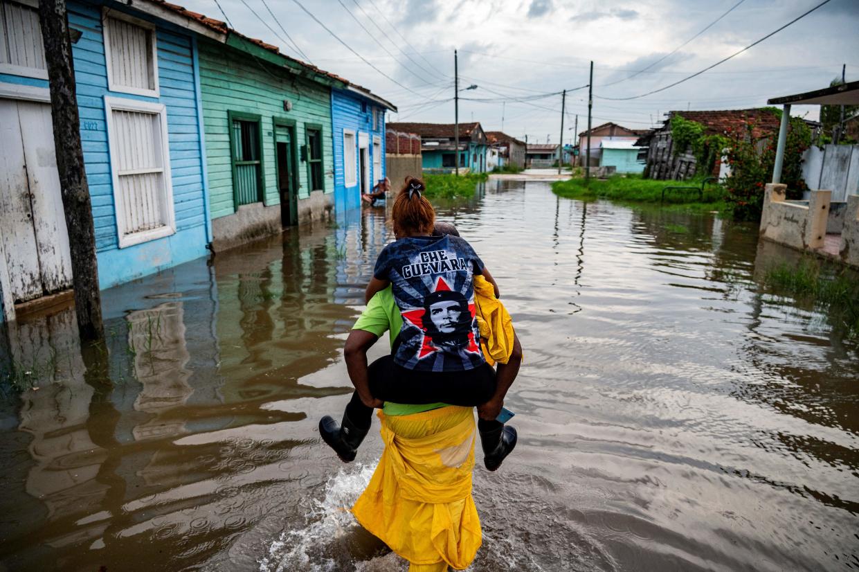A man carries a woman on his back as he wades through the water in a flooded area of Batabano, Mayabeque Province, Cuba (AFP/Getty)