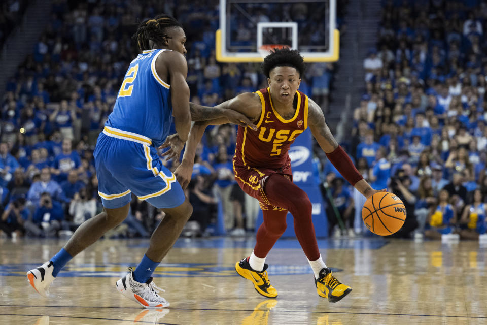 Southern California guard Boogie Ellis (5) drives to the basket as UCLA guard Dylan Andrews (2) defends during the first half of an NCAA college basketball game Saturday, Feb. 24, 2024 in Los Angeles. (AP Photo/Kyusung Gong)