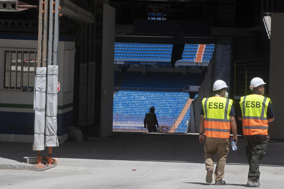 Workers walk into Real Madrid's Santiago Bernabeu stadium in Madrid, Spain, Monday, May 25, 2020. Spanish league clubs are now allowed to train with groups of up to 14 players as the league stays on track to restart in less than three weeks. (AP Photo/Paul White)