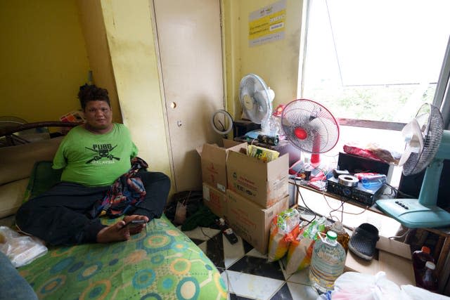 Mohamad Nor Abdullah, born without arms, sits near donated goods, right, in his rented room in Kuala Lumpur, Malaysia (Vincent Thian/AP)