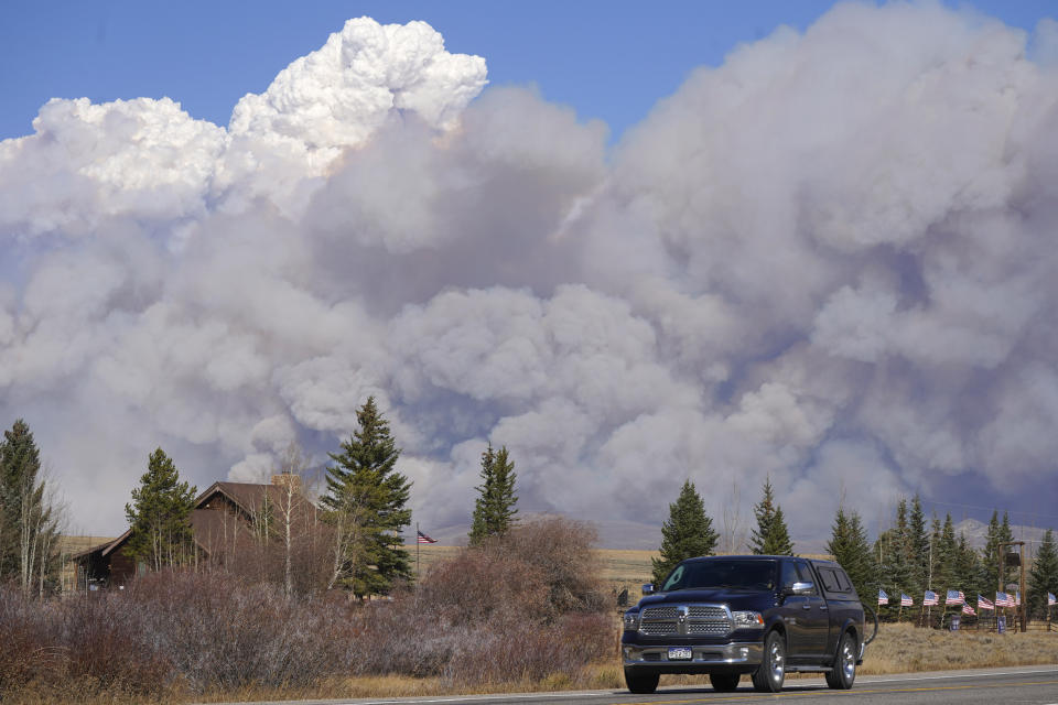 Smoke rises from mountain ridges as a motorist heads eastbound on Highway 34 while a wildfire burns Thursday, Oct. 22, 2020, near Granby, Colo. (AP Photo/David Zalubowski)