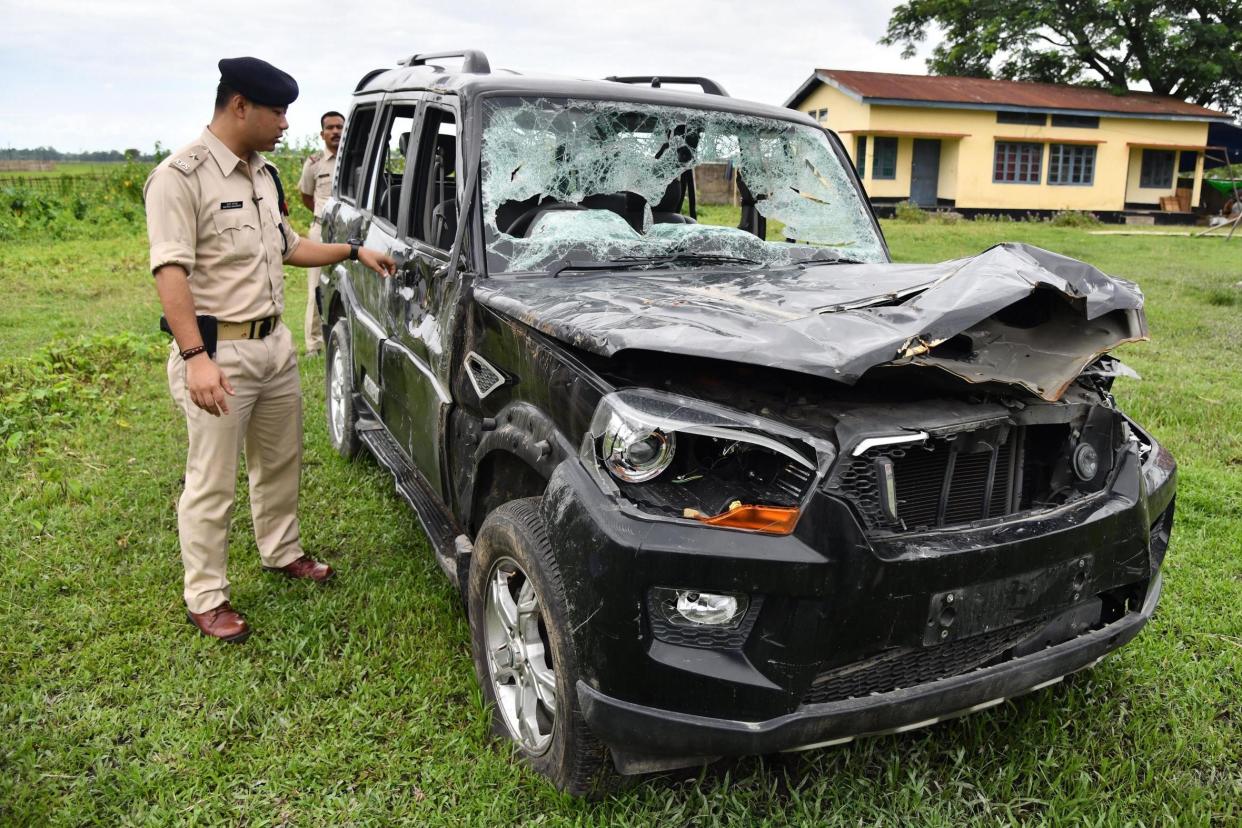 A police officer inspects a damaged vehicle in which two men were lynched in Karbi Anglong, India, in July. Abhijeet Nath and Nilotpal Das were beaten to death following the spread of child abduction rumours on WhatsApp: Biju Boro/AFP/Getty Images