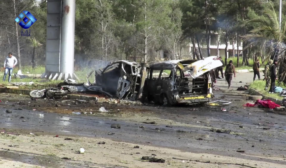 This frame grab from video provided by the Thiqa News Agency, shows rebel gunmen at the site of a blast that damaged several buses and vans at the Rashideen area, a rebel-controlled district outside Aleppo city, Syria, Saturday, April. 15, 2017. Syrian TV said at least 39 people were killed Saturday in an explosion that hit near buses carrying evacuees from two towns besieged by rebels nearby. (Thiqa News via AP)