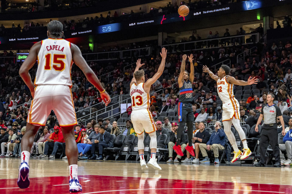 Detroit Pistons guard Marcus Sasser (25) shoots a three-pointer against Atlanta Hawks guard Bogdan Bogdanovic (13) and Atlanta Hawks forward De'Andre Hunter (12) during the first half of an NBA basketball game, Wednesday, April 3, 2024, in Atlanta. (AP Photo/Jason Allen)