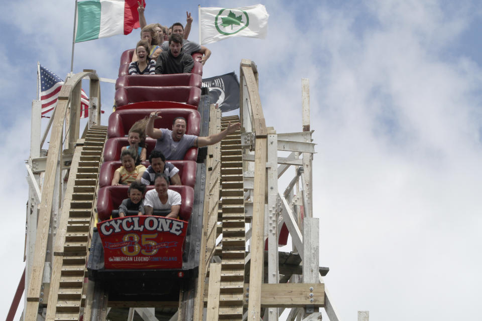 In a Tuesday, June 26, 2012 photo, people ride the Cyclone roller coaster at Coney Island in New York.  The New York City landmark and international amusement icon will be feted Saturday, June 30 with a birthday party in its honor. (AP Photo/Mary Altaffer)