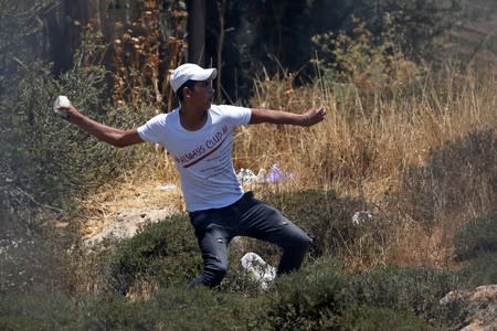 Palestinian demonstrator hurls stones at Israeli forces during a protest against Bahrain's workshop for U.S. peace plan, near Hebron, in the Israeli-occupied West Bank