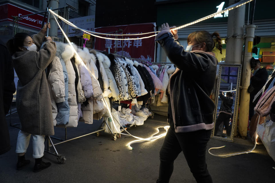 Varias dependientas preparan un puesto en un mercado nocturno de Wuhan. Frente a los confinamientos del resto del mundo, en la ciudad china el coronavirus parece cosa del pasado. (AP Photo/Ng Han Guan)