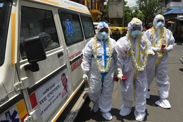 Kolkata Municipal Corporation (KMC) health department staff in PPE coveralls are greeted with garlands and a shower of flower petals before a swab collection exercise for COVID- 19 tests at Ward 68, Golpark  in Kolkata, India.  