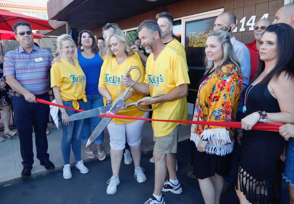 Kelly's Pub and Wine Bar owners Rhonda and Rob Hanson (holding scissors, center) hold a ribbon-cutting ceremony with members of the Redding Chamber of Commerce on Thursday, July 7, 2022. The pub has reopened in a new location at 2144 Hilltop Drive after the couple endured a string of hardships.
