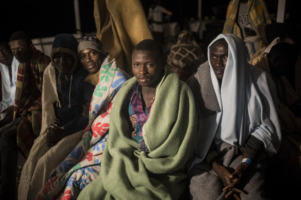 Vafin, 16, centre, from Guinea Conarky, sits with other migrants on the deck of Open Arms vessel, after they were rescued by the Spanish NGO Pro Activa Open Arms, about 40 miles (64 kms) from the Spanish coasts, on Thursday, Oct. 11, 2018. The Open Arms is now based at Motril port in order to start operating in the western Mediterranean area. (AP Photo/Javier Fergo)