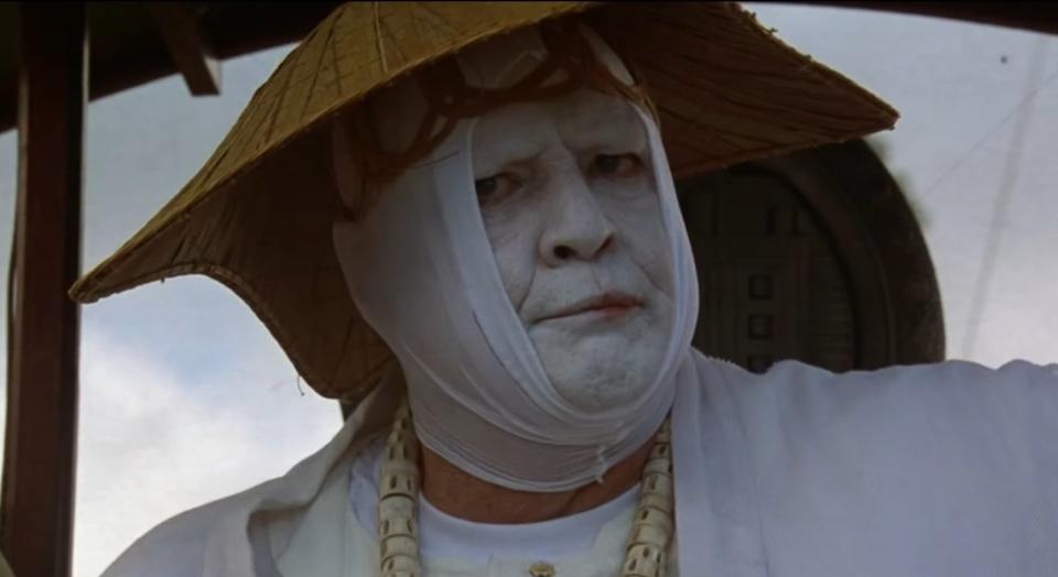 Dr. Moreau wearing a white tunic and matching face paint in "The Island of Dr. Moreau" (1996)