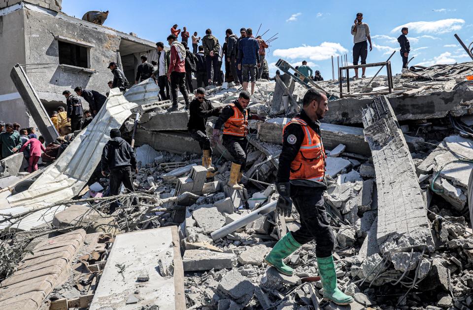 People and first responders search the rubble of a building that collapsed following an Israeli air strike in the Rafah refugee camp in the southern Gaza Strip on March 20, 2024 amid the ongoing conflict in the Palestinian territory between Israel and the militant group Hamas.