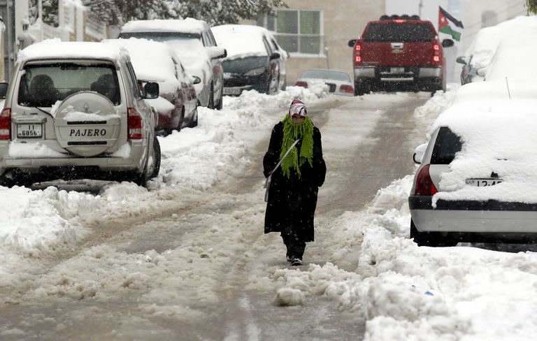 A Jordanian woman walks in a snow-covered street in Amman on January 10, 2013. A blizzard brought the country to a near halt. King Abdullah II ordered the army to help clear roads across the usually parched nation and help those stranded by the snow