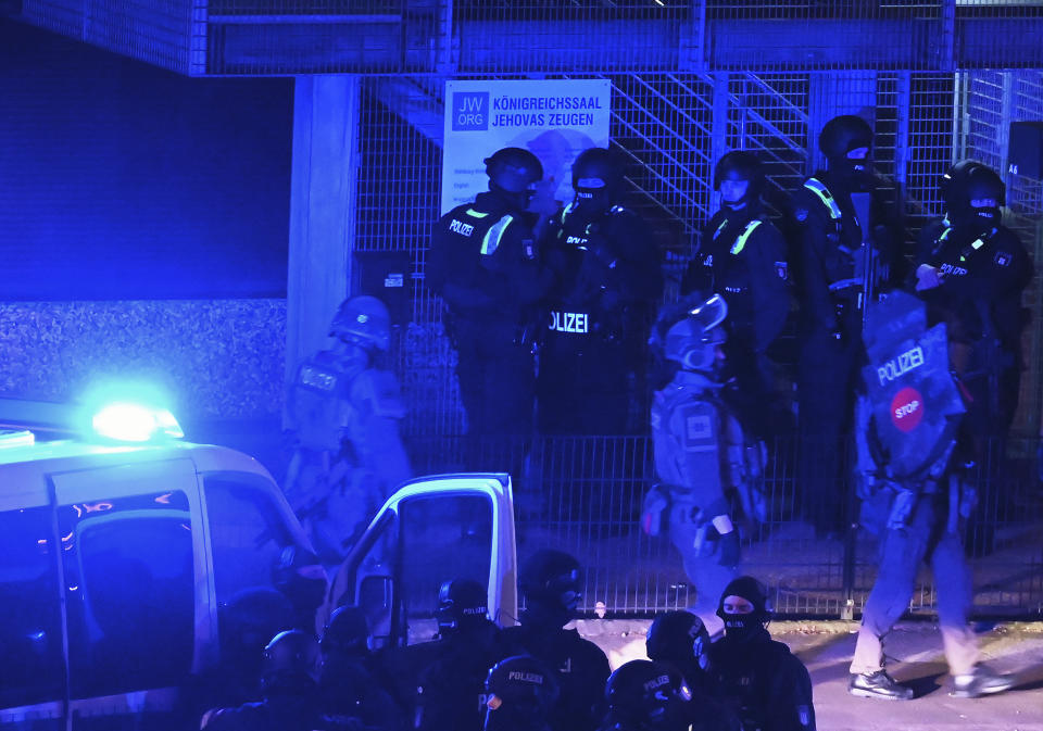 Police officers are on duty in Hamburg, Germany, Thursday, March 9, 2023, standing in front of a sign reading "Kingdom Hall of Jehovah's Witnesses." German authorities say one or more people opened fire in a church in the northern city of Hamburg. (Jonas Walzberg/dpa via AP)