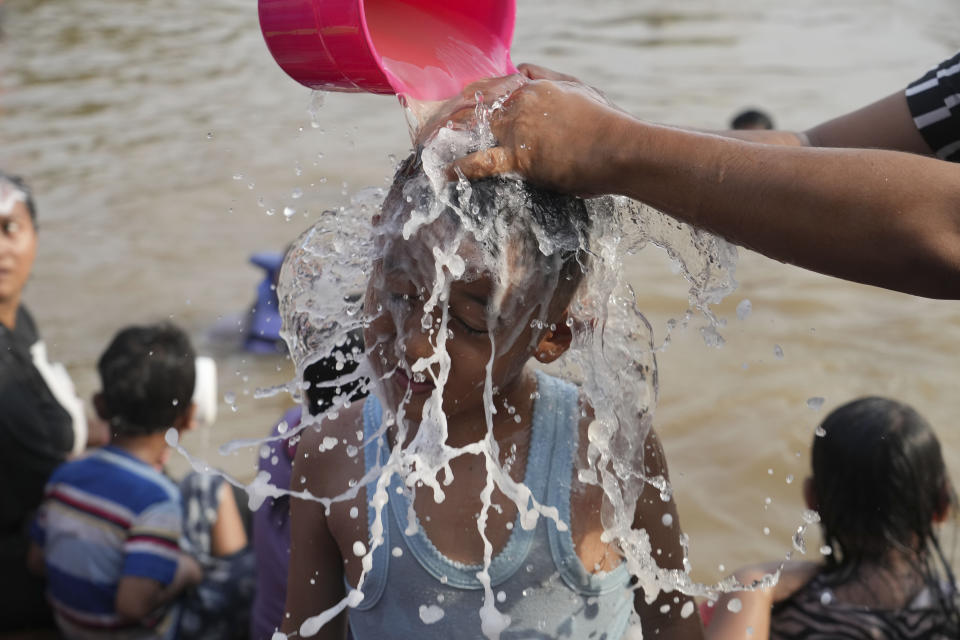 A woman is helped to take shower in the Cisadane River, ahead the holy fasting month of Ramadan in Tangerang, Indonesia, Tuesday, March 21, 2023. Muslims followed local tradition to wash in the river to symbolically cleanse their soul prior to entering the holiest month in Islamic calendar. (AP Photo/Tatan Syuflana)