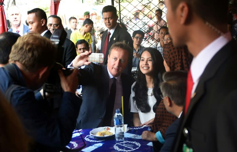 Prime Minister David Cameron (centre L) takes a selfie with Indonesian actress and former Oxford student Maudy Ayunda (centre R) after ordering local food from a streetside stall in Jakarta on July 28, 2015