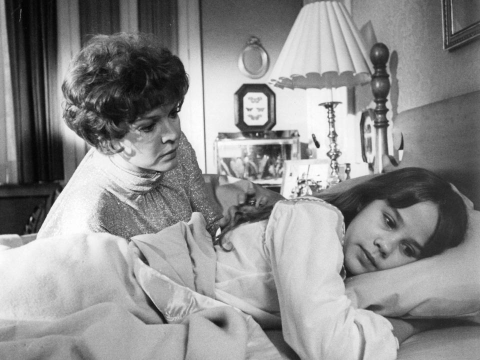 Ellen Burstyn reaches over Linda Blair who lays with head on pillow in a scene from the film 'The Exorcist', 1973.