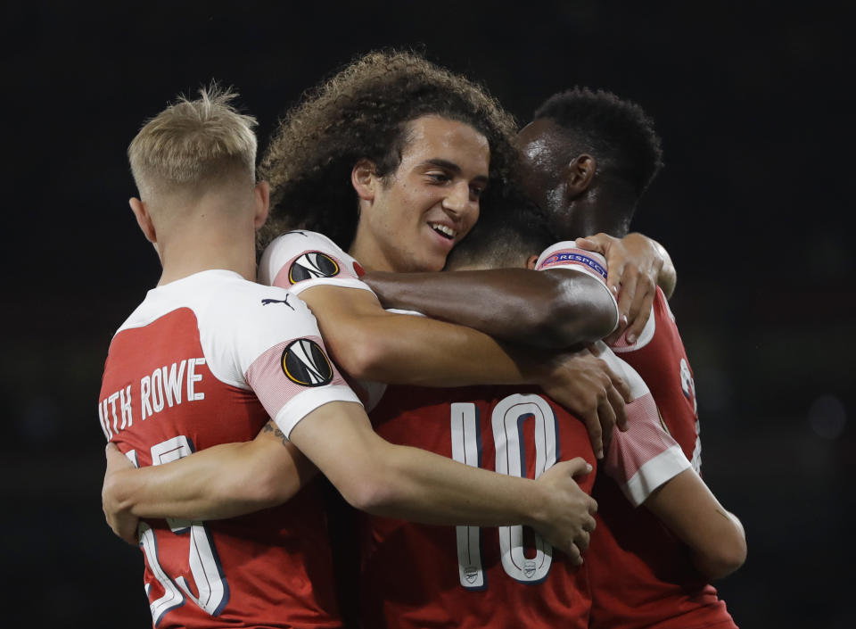 Arsenal's players embrace Mesut Ozil after he scored his side's 4th goal during the Europa League Group E soccer match between Arsenal and Vorskla in London, England, Thursday, Sept. 20, 2018. (AP Photo/Kirsty Wigglesworth)