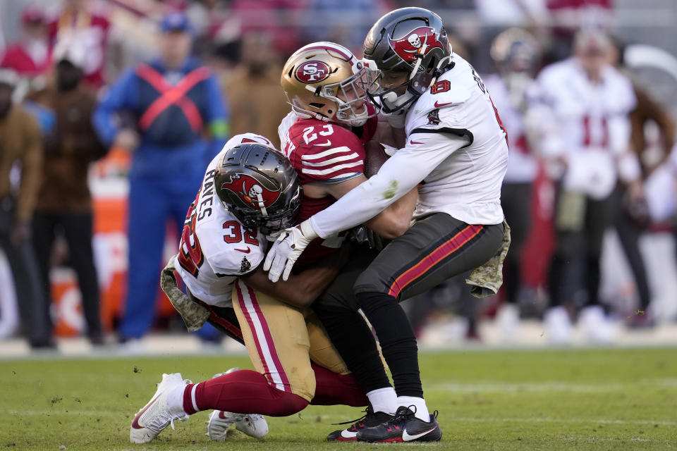 San Francisco 49ers running back Christian McCaffrey, middle, is tackled by Tampa Bay Buccaneers safety Josh Hayes (32) and linebacker SirVocea Dennis during the second half of an NFL football game in Santa Clara, Calif., Sunday, Nov. 19, 2023. (AP Photo/Godofredo A. Vásquez)