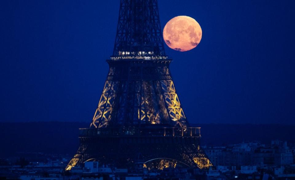 This photograph taken in Paris on April 23, 2024, shows the April's full moonset, also known as the Pink Moon, seen behind the Eiffel Tower.