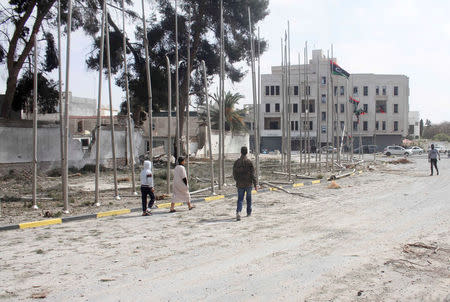 Libyans walk past a damaged compound occupied by a self-declared rival prime minister after it was taken over by armed groups aligned with a U.N.-backed government in heavy fighting, in Tripoli, Libya, March 15, 2017. REUTERS/Hani Amara