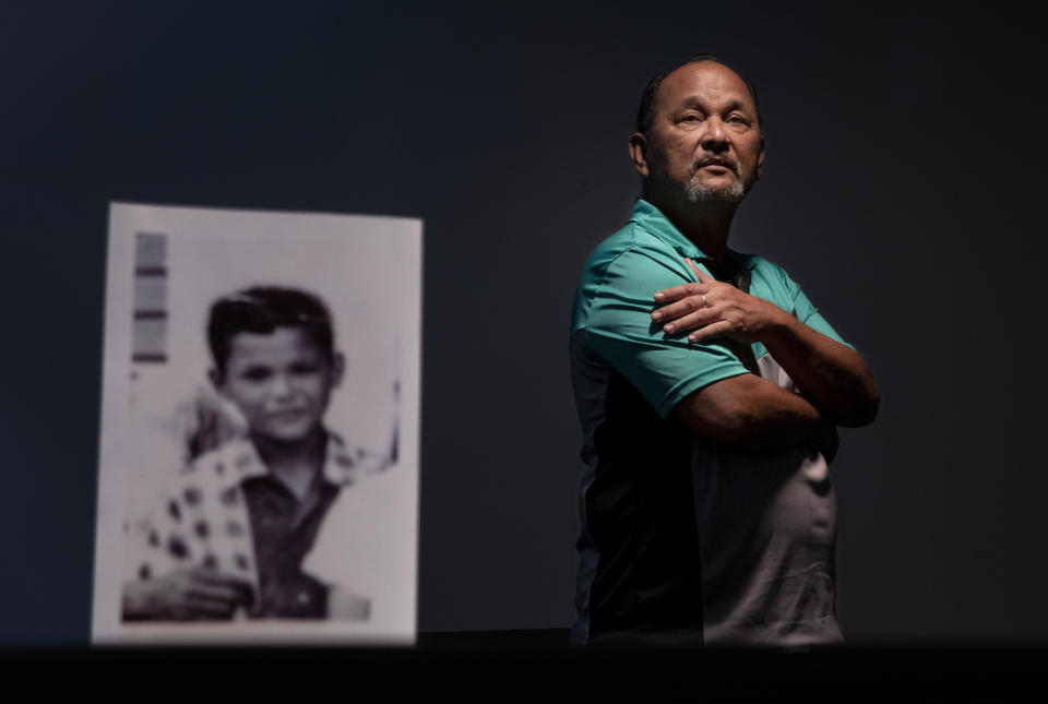 Ramon De Plata, 65, stands behind a photo of himself when he was about 10 years old, the age when he says he walked into Father Antonio Cruz's bedroom and saw Cruz and his protege, seminarian Anthony Apuron, engaged in sex acts with a boy from his school, Monday, May 13, 2019, in Hagatna, Guam. "He was calling me to join them," recounted De Plata. "It really messed me up growing up. I became hostile in school. I didn't trust my teachers anymore. I was picking on other kids, harassing them, calling them names. ... Even now, I'm always on guard." Cruz is dead, and Apuron denies the allegations. (AP Photo/David Goldman)