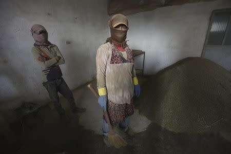 A 29-year old women (R) and her 13-year-old relative (who asked to withhold their names) talk while sweeping cannabis into a pile inside a garage in the Bekaa valley, Lebanon November 1, 2015.REUTERS/Alia Haju