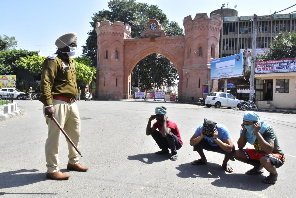 AMRITSAR, INDIA - MARCH 25: Police personnel make curfew violators perform sit-ups, on the first day of the 3-week national lockdown to check the spread of coronavirus, at Hall Gate on March 25, 2020 in Amritsar, India. Prime Minister Narendra Modi on Tuesday announced a complete lockdown of the entire country for 21 days in an unprecedented drastic measure to try halt the spread of coronavirus as the number of cases in the country crossed 500. (Photo by Sameer Sehgal/Hindustan Times via Getty Images)