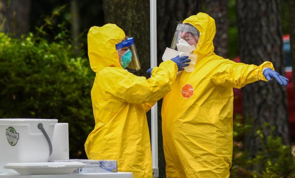 A worker uses disinfectant wipes to clean the personal protective equipment of a worker who just administered a nose swab at the free COVID-19 test site on Thursday, May 28, 2020 at the Elijah Washington Medical Center in Sheldon.