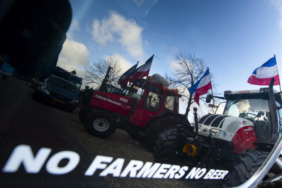 Tractors are reflected in a car window during a farmers demonstration in The Hague, Netherlands, Wednesday, Feb. 19, 2020. Dutch farmers, some driving tractors, poured into The Hague on Wednesday to protest government moves to rein in carbon and nitrogen emissions to better fight climate change. (AP Photo/Peter Dejong)