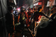 Indonesian rescue team carry a victim of fire at a neighborhood in Jakarta, Indonesia, Friday, March 3, 2023. A large fire broke out at a fuel storage depot in Indonesia's capital on Friday, killing several people, injuring dozens of others and forcing the evacuation of thousands of nearby residents after spreading to their neighborhood, officials said.(AP Photo/Achmad Ibrahim)
