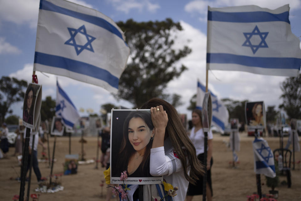 A woman touches a picture of a relative as she attends the celebrations of the Israel's annual Memorial Day for the fallen soldiers, at the site where revelers were killed and kidnapped on Oct. 7 cross-border attack by Hamas militants at the Nova music festival near the Kibbutz Reim, southern Israel, Monday, May 13, 2024. Israel marks the annual Memorial Day for fallen soldiers and victims of nationalistic attacks. (AP Photo/Leo Correa)