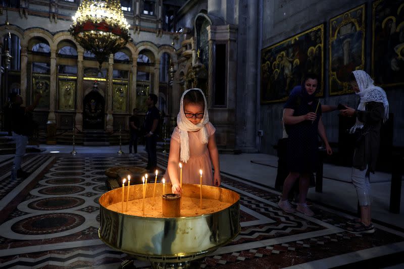 FILE PHOTO: A girl places a candle in the Church of the Holy Sepulchre in Jerusalem's Old City