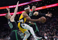 Indiana Pacers forward Bruce Brown, center, passes the ball while pressured by Boston Celtics center Kristaps Porzingis, right, and forward Sam Hauser during the first half of an NBA basketball game Wednesday, Nov. 1, 2023, in Boston. (AP Photo/Charles Krupa)