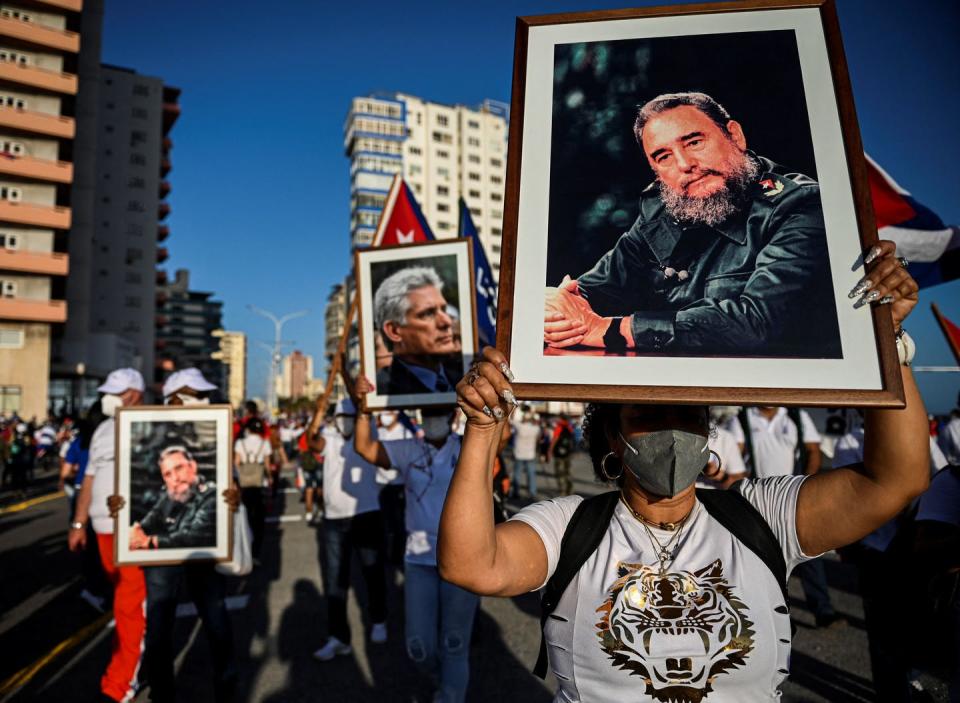 Marchers on street hold pictures of Cuban leaders