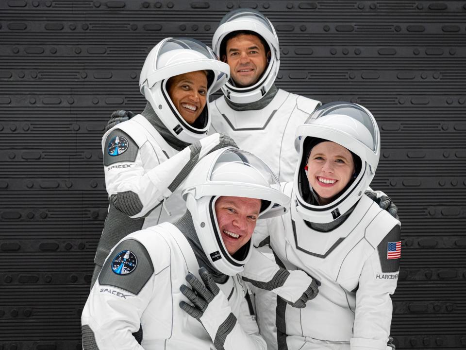 inspiration4 crew members pose in spacesuits in front of grey wall