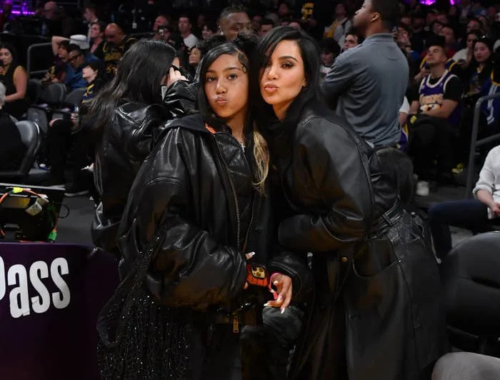 Kim Kardashian and her daughter North West posing together courtside, making kissy faces, at a basketball game