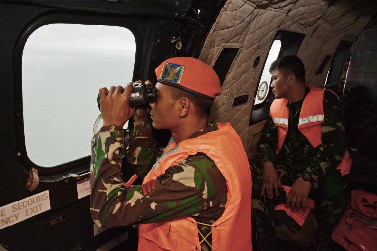 A crewmember of an Indonesian Air Force Super Puma helicopter scans the horizon during search operations for victims of AirAsia Flight QZ8501 over the Java Sea on January 1, 2015