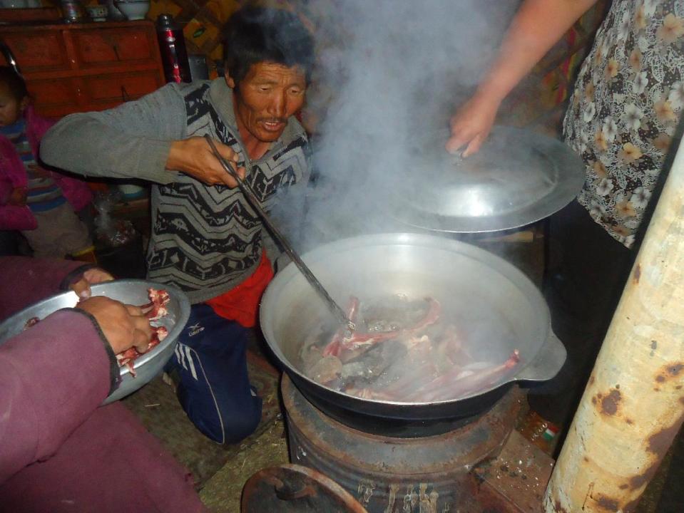 In this Sept. 11, 2011 photo, a nomad stirs a large pot full of mutton, potatoes and carrots cooked with hot stones. The festive meal, called the khorkhog, is the highlight of nomadic cuisine, and its preparation is a group project. (AP Photo/Louise Chu)