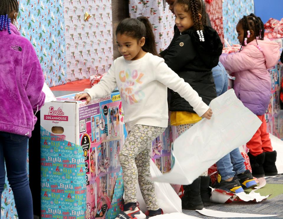 Adele Avance, 8, opens her gift Tuesday, Dec. 13, 2022, at the Forever 7 Barbie Dream House gift distribution at the Excel Center in South Bend for 24 girls in the memory of Chrisyah Stephens.