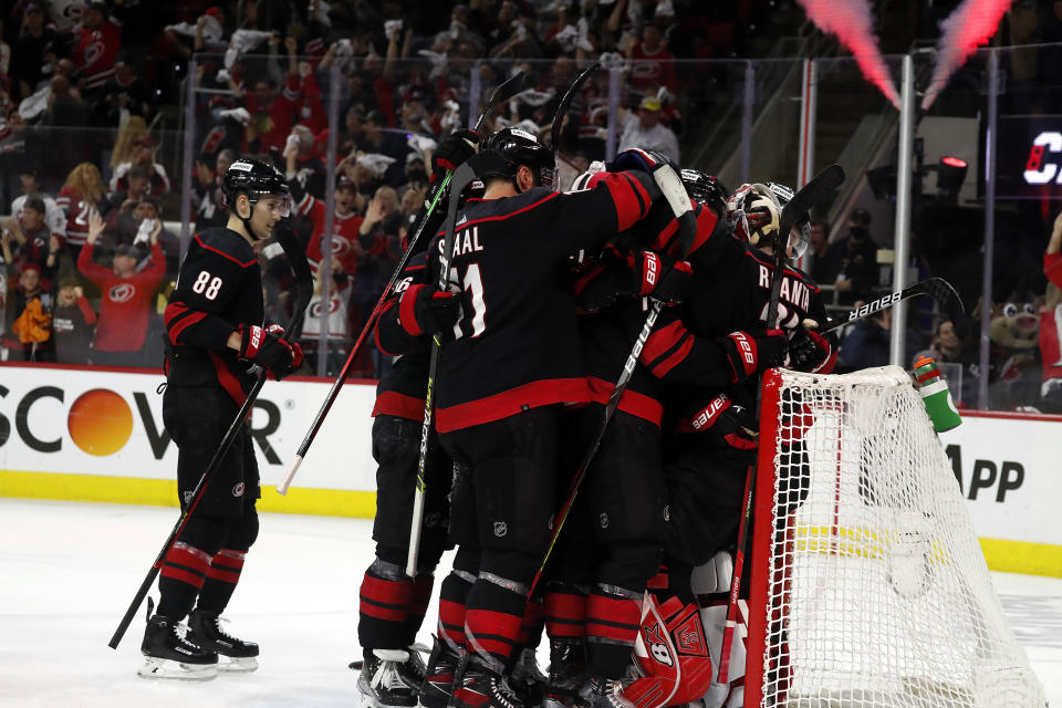 Carolina Hurricanes players celebrate around goaltender Antti Raanta following their win over the Boston Bruins in Game 7 of an NHL hockey Stanley Cup first-round playoff series in Raleigh, N.C., Saturday, May 14, 2022. (AP Photo/Karl B DeBlaker)