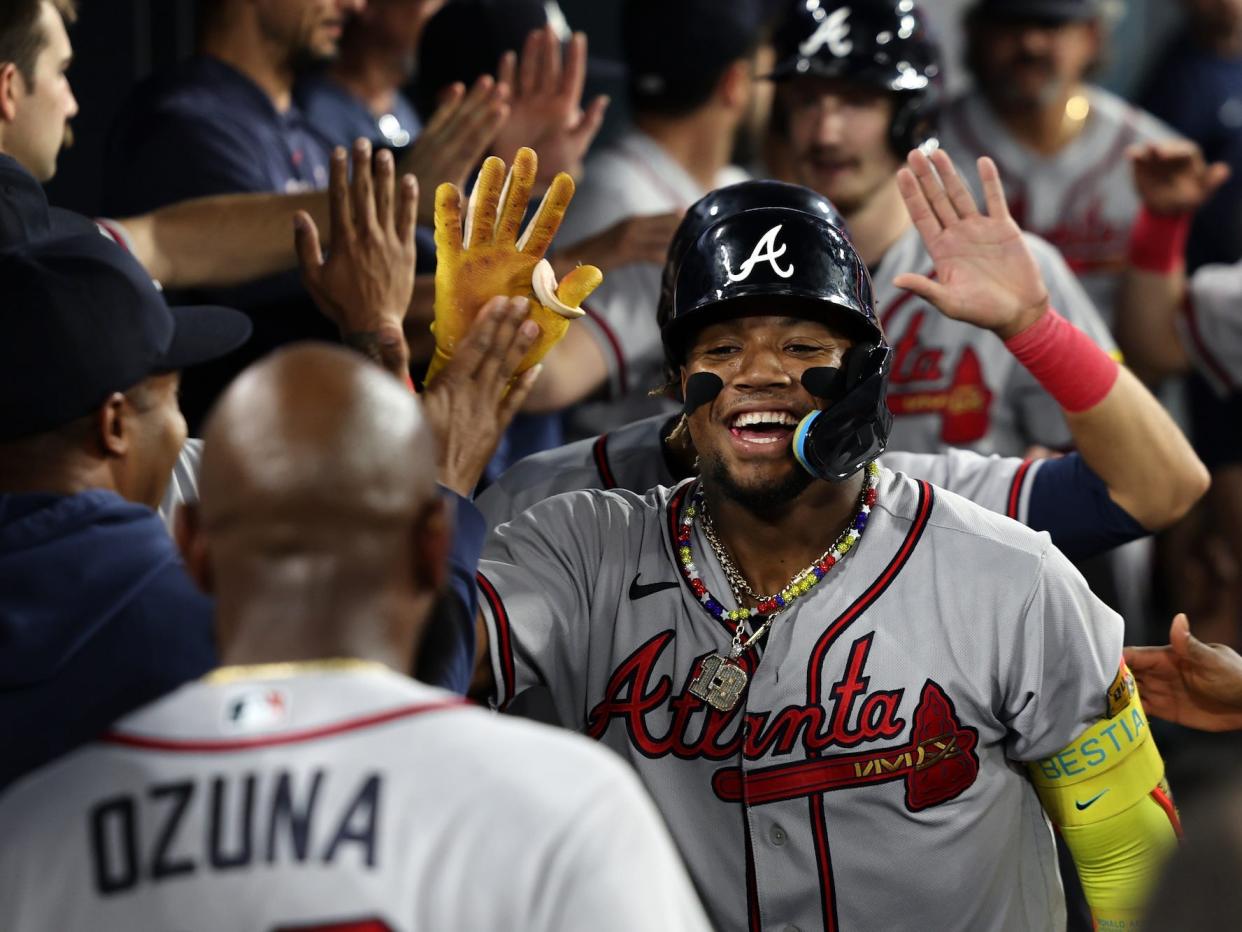 Ronald Acuña Jr. raises his hand to high-five his teammates.