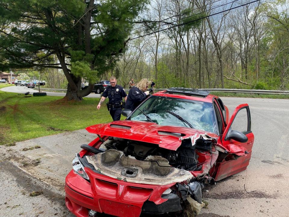 Mansfield police Crime Lab technician Cindy Reed takes photographs of a car which was involved in a two-vehicle crash on Fifth Avenue Thursday afternoon. The occupants of the red car fled on foot from officers and after removing their license plate.