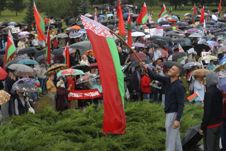 A man waves a Belarusian State flag as supporters of Belarusian President Alexander Lukashenko gather in a square in Minsk, Belarus, Wednesday, Aug. 19, 2020. Belarus' authoritarian leader threatened Wednesday to take tough new steps against demonstrators challenging the extension of his 26-year rule and accused the West of fomenting unrest as he sought to consolidate his grip on power amid widening protests. (AP Photo/Sergei Grits)