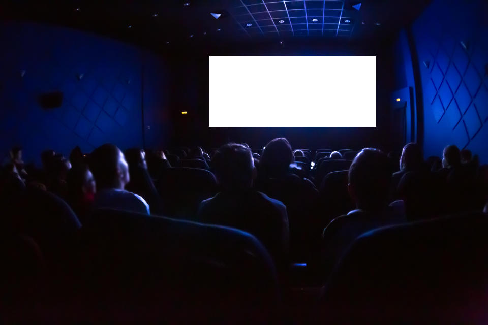 People in the cinema watching a movie. Blank empty white screen.